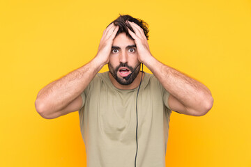 Telemarketer man working with a headset over isolated yellow background with surprise facial expression