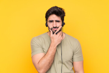 Fototapeta na wymiar Telemarketer man working with a headset over isolated yellow background thinking an idea