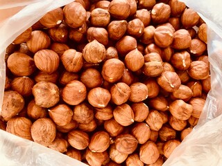 Fresh whole peeled hazelnuts in a open plastic bag in soft focus.