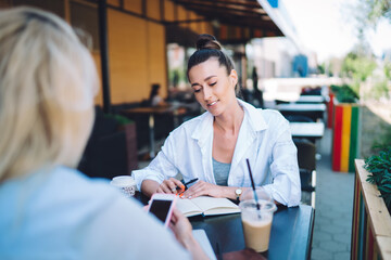 Positive woman speaking to coworker on summer terrace during coffee break