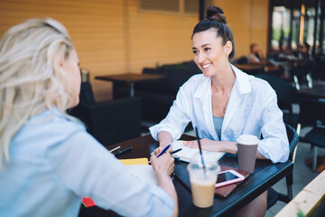 Smiling woman listening to colleague at table in cafe