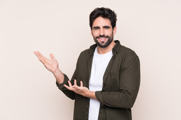 Young handsome man with beard over isolated background extending hands to the side for inviting to come