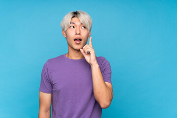 Young asian man over isolated blue background thinking an idea pointing the finger up © luismolinero