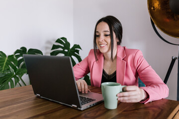 Fototapeta premium business woman working at her wooden table while holding a green cup of coffee