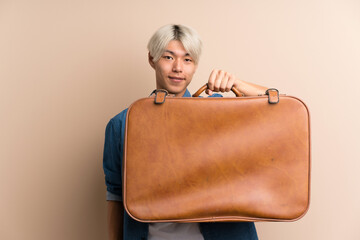 Young asian man over isolated background holding a vintage briefcase