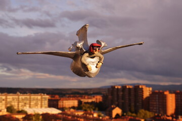 TOY PILOT FLYING OVER A CITY ON A SILVER COW VERTEBRA AT SUNSET