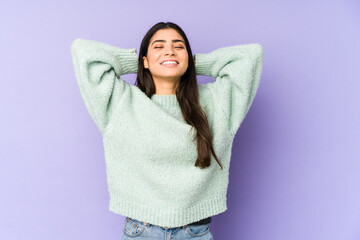 Young indian woman isolated on purple background feeling confident, with hands behind the head.