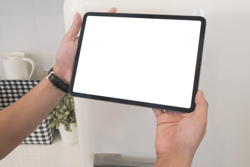 Cropped shot of hands holding digital labtop with blank screen in kitchen.