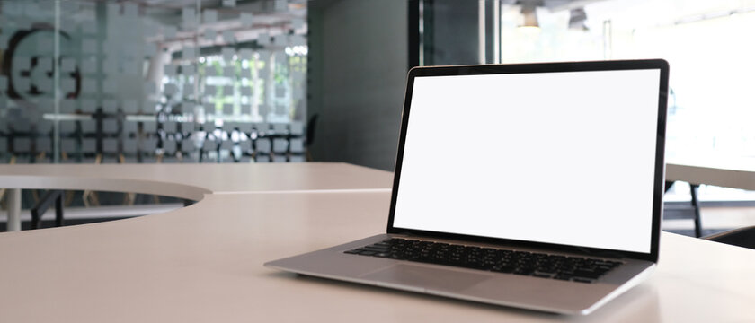 Mock up image of laptop with white screen on white table and copy space with office background.