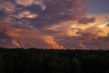 Obraz premium There are dramatic clouds in the dark sky as the sun sets. The sky is dominated by fuchsia, pink.