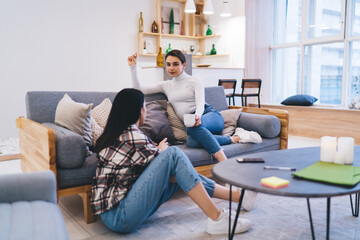 Young female friends discussing relationship in spacious living room