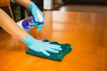 Sanitizing surfaces cleaning kitchen table with disinfectant spray bottle with towel and gloves....