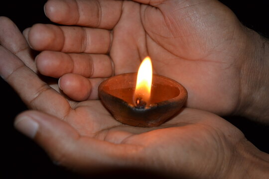 Hands holding a traditional candle also known as &acute;diyo&acute; or &acute;diya&acute; in South Asian countries like Nepal and India. This is used mainly in Hindu festivals like Dussehra and Deepawali.