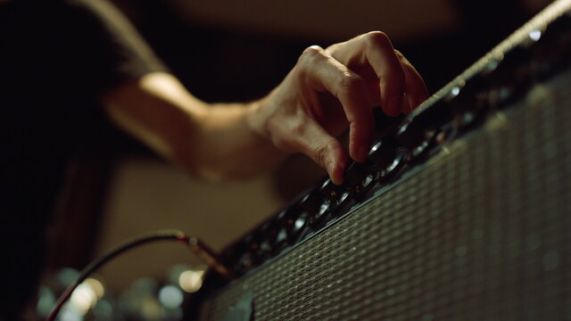 Unrecognizable person preparing equipment in studio. Man hand turning knobs.