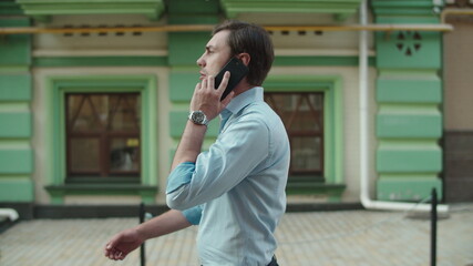 Serious business man talking phone outdoors. Businessman walking with smartphone