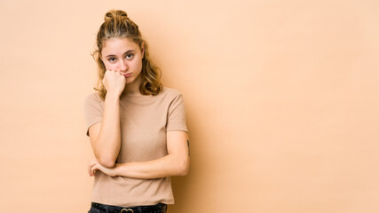 Young caucasian woman isolated on beige background who feels sad and pensive, looking at copy space.