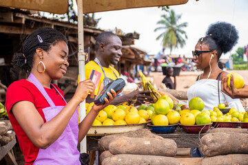 people in a local african market, trader swiping a credit card on a pos machine