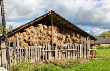 Hay storage with harvested bales of hay for cattle. Agricultural barn canopy with bales hay