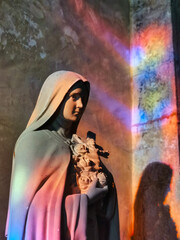 Saint therese of lisieux statue, with magnificent stained glass reflections, in a french catholic church.