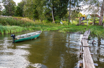 Plastic fishing boat with motor on the bank of the lake in summer day