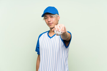 Young asian man playing baseball over isolated green background