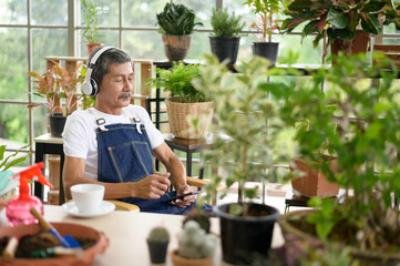 Happy senior asian retired man listening to music  and enjoying  leisure activity in garden at home.