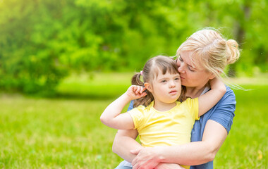 Happy family. Mom and her little daughter with syndrom down have a fun in summer park. Empty space...