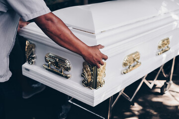 Pallbearer's hand pushing the coffin during funeral procession. Selective focus.