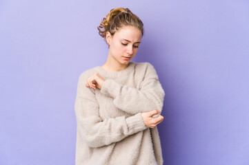 Young caucasian woman on purple background massaging elbow, suffering after a bad movement.