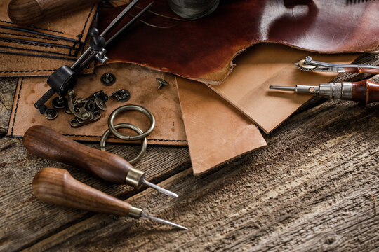 Leather craft tools on old wood table. Leather craft workshop.