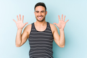 Young caucasian man isolated on blue background showing number ten with hands.