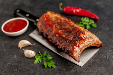grilled pork ribs on a meat knife on a stone background