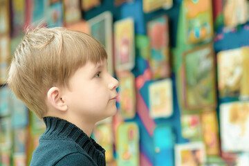 The boy looks at the paintings at the exhibition of pictorial ar