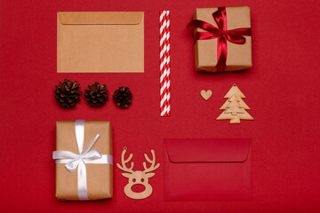 Christmas composition. Christmas gifts, wooden toys, pine cones on red background top view