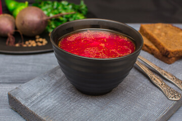 Borsch is a traditional Ukrainian soup. Vegetable soup with sour cream in a ceramic cup on an old wooden surface.