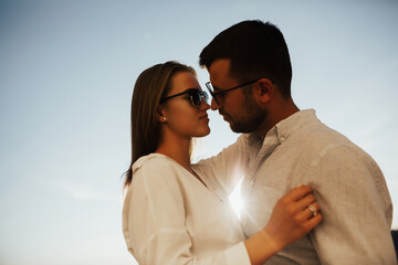 A close up portrait of two lovers in sunglasses looking at each other. They are going to kiss. Copy space.