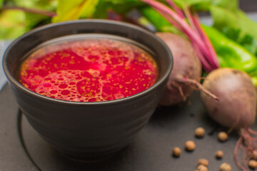 Borsch is a traditional Ukrainian soup. Vegetable soup with sour cream in a black ceramic cup on a black metal serving.