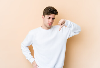 Young caucasian man isolated on beige background showing thumb down, disappointment concept.