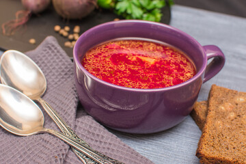 Borsch is a traditional Ukrainian soup. Vegetable soup with sour cream in a ceramic cup on an old wooden surface.