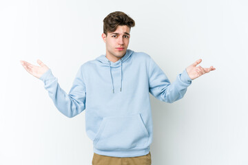 Young caucasian man isolated on white background doubting and shrugging shoulders in questioning gesture.