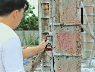 Man holding electric laser tape measure, Laser measuring device,red machine in hand, steel concrete...