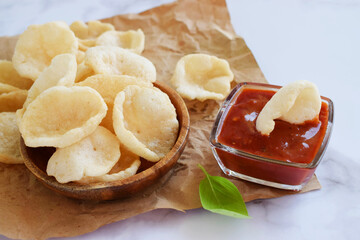 Prawn Crackers or Shrimp Chips with ketchup served on parchment paper, Fresh Krupuk on bright background.