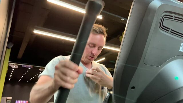 Man in gym does cardio exercise with Holter monitoring device on chest