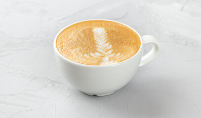White cup of hot cappuccino coffee on concrete background