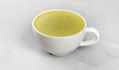White cup of hot matcha coffee on concrete background