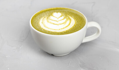 White cup of hot matcha coffee on concrete background
