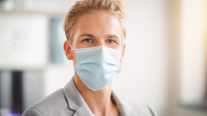 Portrait of the Handsome Stylish Young Man Wearing Protective Face Mask Inside. Blue Eyed Blond...