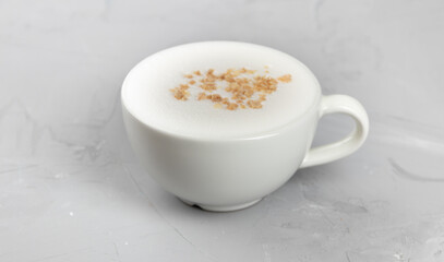 White cup of hot coffee with nuts on concrete background
