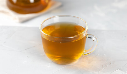 Yellow tea in a glass transparent cup with hot water on a concrete background
