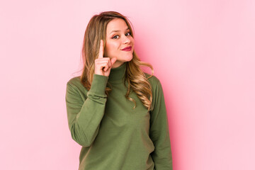 Young caucasian woman isolated on pink background showing number one with finger.